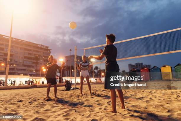 teenage kids playing volleyball on beach in city of alicante - beach volleyball stockfoto's en -beelden