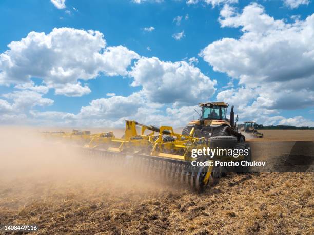 drone view of a yellow tractor preparing soil in wheat field after harvesting. soil preparation with agricultural machinery. - land clearing stock pictures, royalty-free photos & images