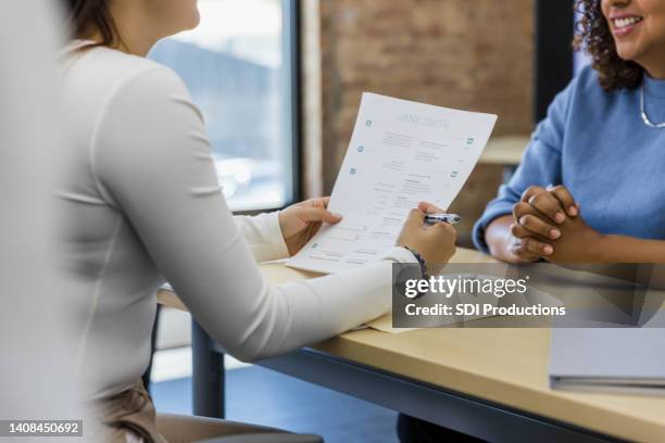 woman clasps hands and smiles during interview - résumé stock pictures, royalty-free photos & images