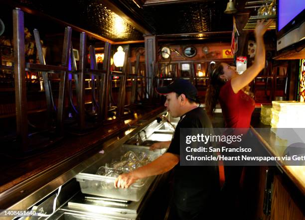 Roger Briceno, left, and Ruby Hernandez remove cocktail glasses from the bar at the TGI Friday's restaurant in San Bruno, Calif., on Tuesday, Dec....