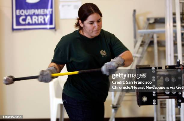 Laura Rouzer swings a sledge hammer, one of a series of eight physical exercises that represent some of the on the job activities of a firefighter,...