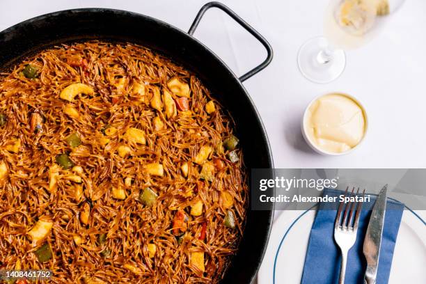 fideua (noodle paella) with seafood served in a restaurant, directly above view - paella stock-fotos und bilder