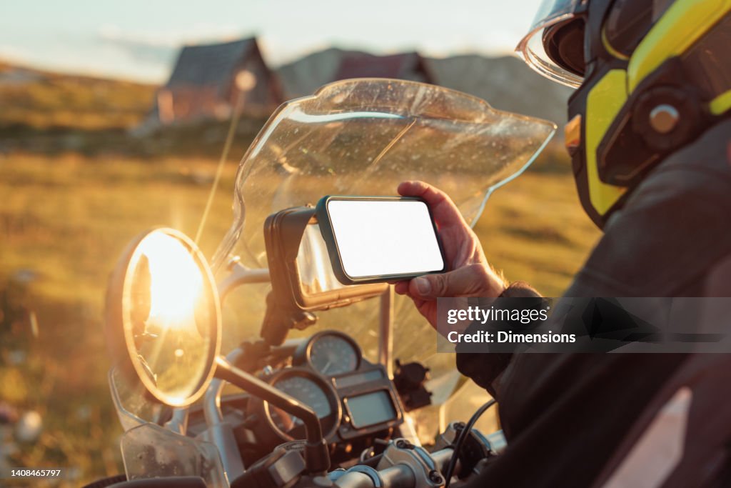 Motorradfahrer, der die Navigation auf dem Mobiltelefon einstellt
