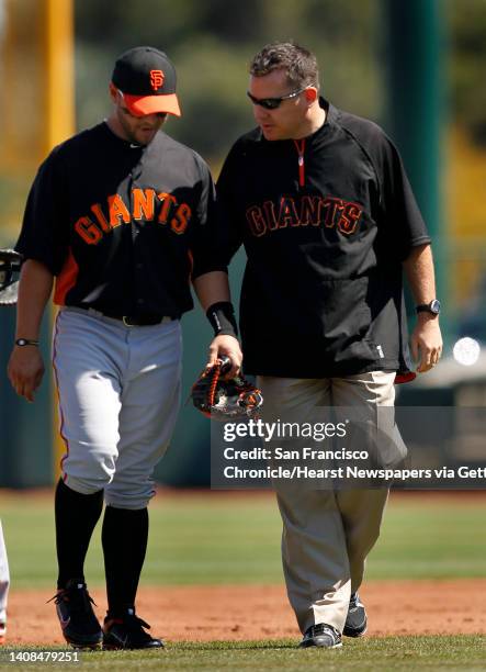 Team trainer Dave Groeschner tends to Cody Ross, who pulled up lame after fielding a fly out in the 1st inning of the Giants' 8-0 loss to the Los...