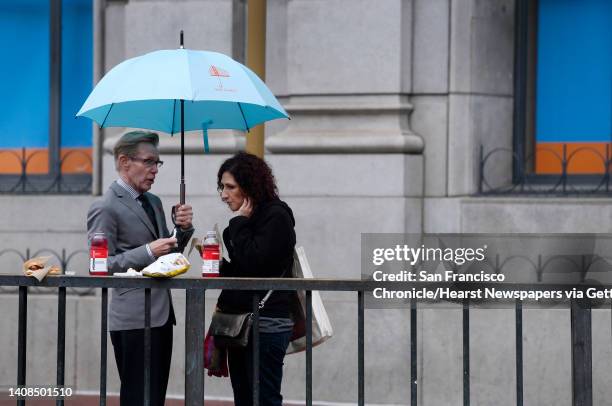 Gregg Solem and Leah Friedman eat lunch under an umbrella in the rain at Hallidie Plaza in San Francisco, Calif. On Wednesday, March 9, 2016.