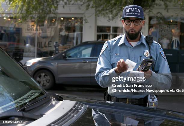 Trevor Adams, a parking control officer for the SFMTA, prints a parking ticket to a car parked at an expired meter on Chestnut Street in the Marina...