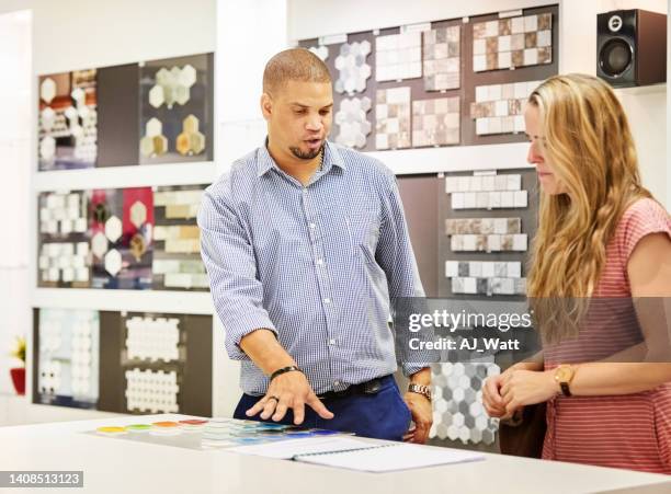 seller offering guidance to a woman customer in tile shop - tile showroom stock pictures, royalty-free photos & images