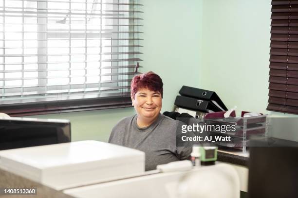 portrait of an office clerk sitting at her desk - older woman colored hair stock pictures, royalty-free photos & images