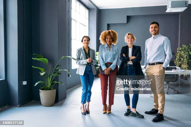 portrait of happy businesspeople standing in a row at their company - four in a row stock pictures, royalty-free photos & images