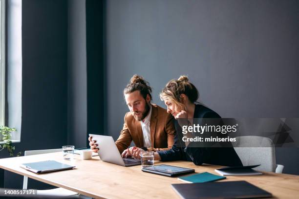 zwei lächelnde kollegen arbeiten gemeinsam an einem neuen projekt - businessman working on a laptop with a coffee stock-fotos und bilder