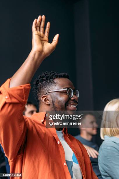 smiling man in the audience raising his hand to ask a question on a education event - teacher taking attendance stock pictures, royalty-free photos & images