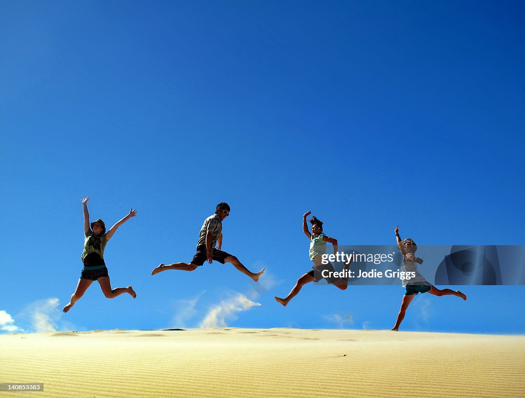People jumping on sand dune