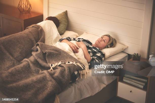 a hopeless woman depressed having a sleepless night inside her bedroom. unhappy female with insomnia lying next to her partner in the evening. lady thinking about divorce in her bed and staring - naast stockfoto's en -beelden