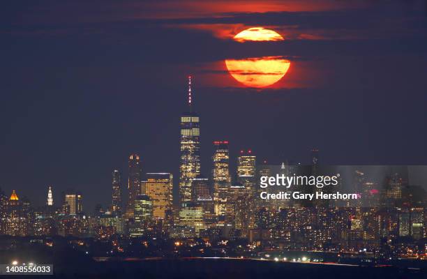 The full Buck Supermoon or Thunder Moon rises above lower Manhattan and One World Trade Center in New York City on July 13 as seen from Verona, New...