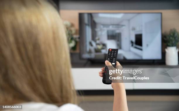 woman relaxing on the couch. attractive casual girl feel happy and relax. female is using the remote control and choosing a tv show or movie on the television menu - video on demand foto e immagini stock