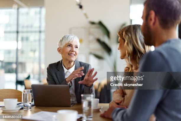 happy female insurance agent talking to a couple on a meeting in the office. - bank loan stockfoto's en -beelden