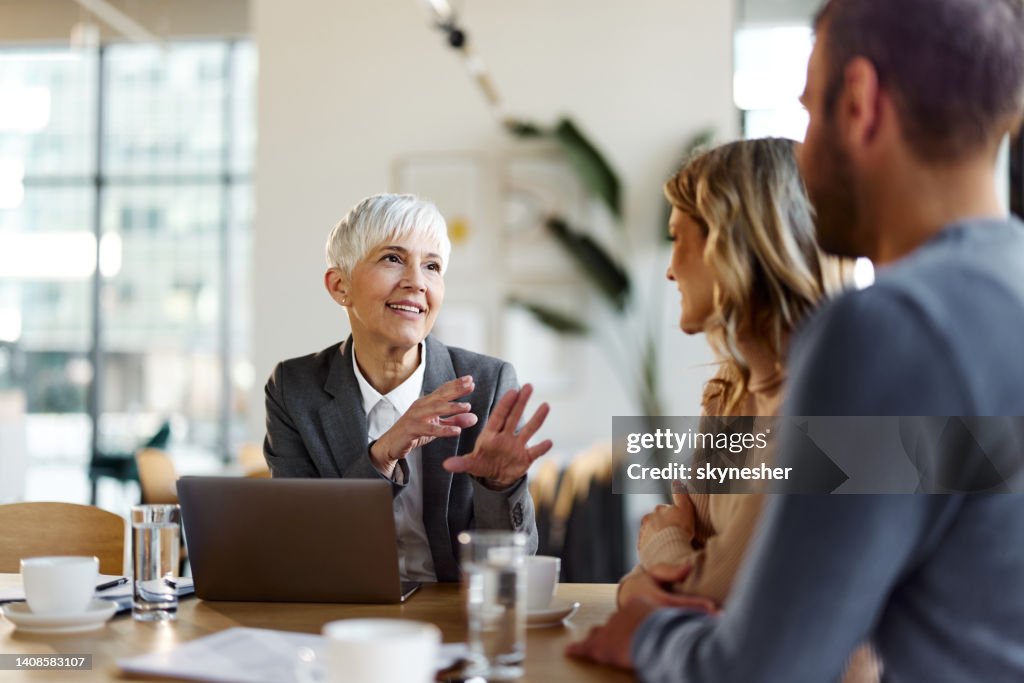 Happy female insurance agent talking to a couple on a meeting in the office.