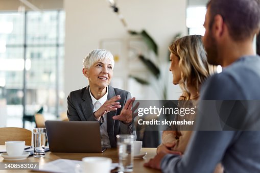 Happy female insurance agent talking to a couple on a meeting in the office. Happy female insurance agent talking to a couple on a meeting in the office.