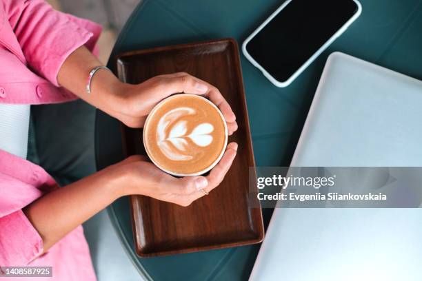 asian businesswoman hands holding cup of hot coffee that standing on the table in cafe at street. - hand resting on wood stock-fotos und bilder