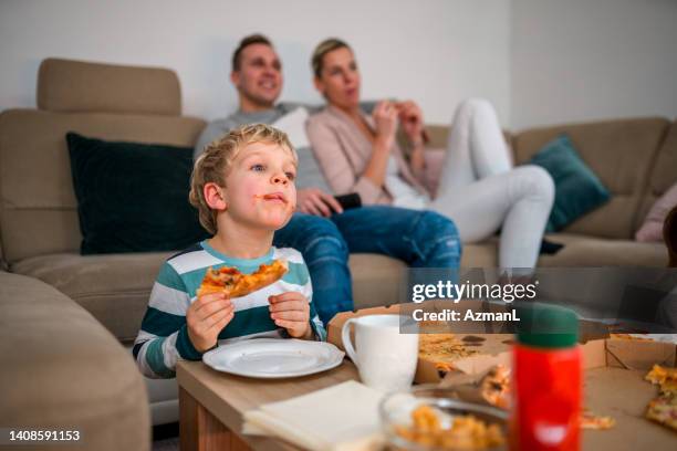 little blond boy with messy mouth, eating pizza with parents - imperfection stock pictures, royalty-free photos & images