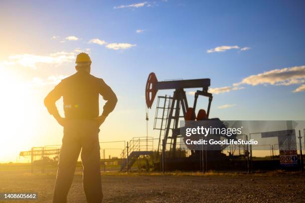 oil worker in front of a pumpjack - behind sun stock pictures, royalty-free photos & images