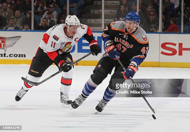 Daniel Alfredsson of the Ottawa Senators skates against Andrew MacDonald of the New York Islanders at Nassau Veterans Memorial Coliseum on February...