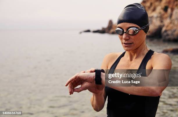 beautiful female swimmer checking her fitness tracker watch after a swim in ibiza - female swimmer bildbanksfoton och bilder