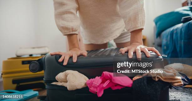 nahaufnahme einer jungen asiatischen frau, die koffergepäck für die reise im wohnzimmer zu hause packt. - suitcase close stock-fotos und bilder