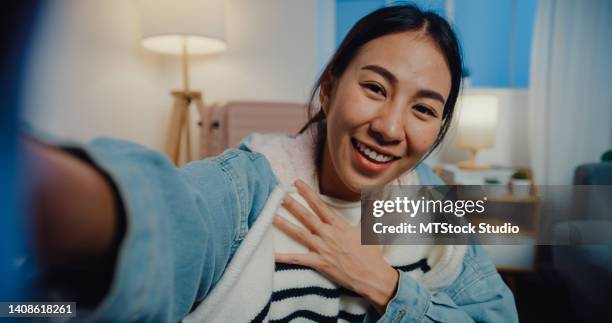 junge asiatische bloggerin, die ein video-selfie aufnimmt, während sie koffergepäck packt, um nachts im wohnzimmer zu hause zu reisen. - man talking to camera stock-fotos und bilder