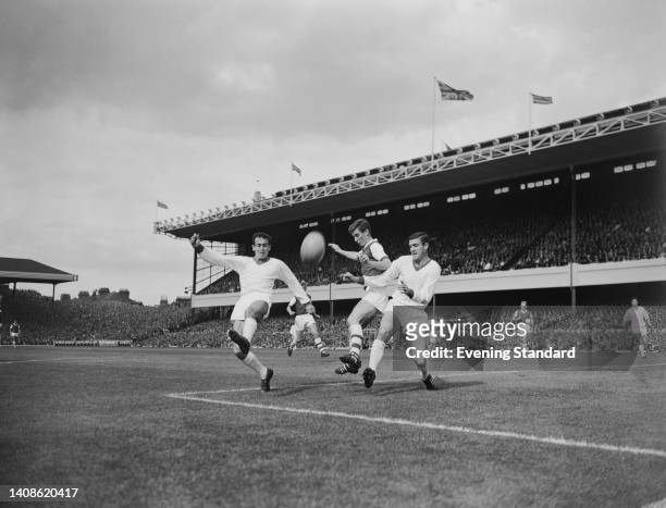 British footballer Shay Brennan , Manchester United defender, clears the ball from British footballer Geoff Strong , Arsenal forward, who is under...