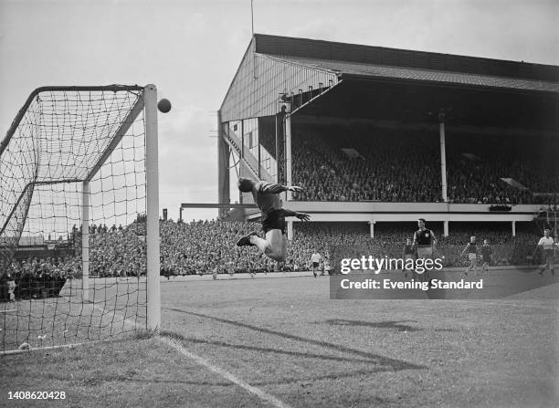 British footballer Lawrie Leslie , West Ham goalkeeper, dives to make the save as the ball clears the crossbar during the English League Division One...