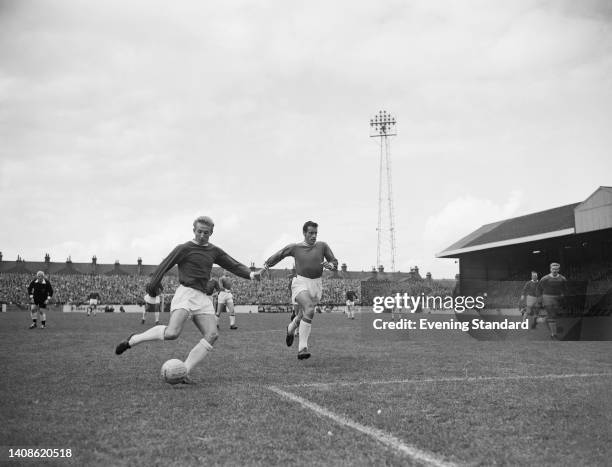 British footballer Denis Law, Manchester United centre forward, under pressure from British footballer Sid Bishop , Leyton Orient defender, during...