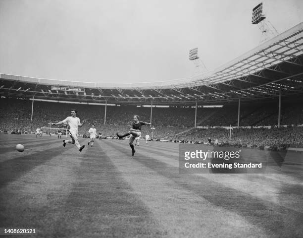 British footballer Richie Norman, Leicester defender, fails to stop the cross from British footballer Bobby Charlton, Manchester United forward, into...