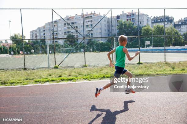 boy running on outdoor track - boy running track stock pictures, royalty-free photos & images