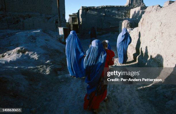 Unidentified women and their children walk in a residential area on July 23, 1996 in Herat, Afghanistan. These women are not allowed to study or work...