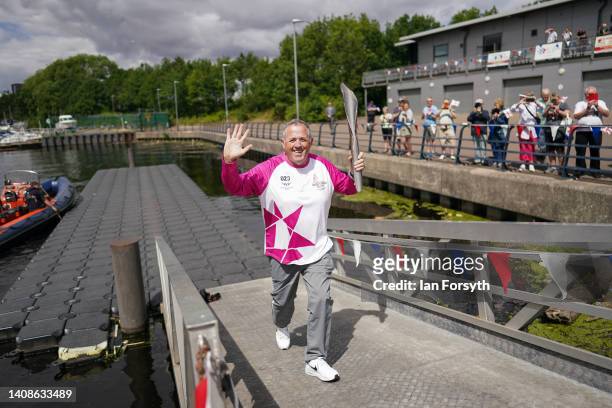 Batonbearer Richard Kilty carries the Queen's Baton during the Birmingham 2022 Queen's Baton Relay on a visit to the River Tees Watersports centre on...