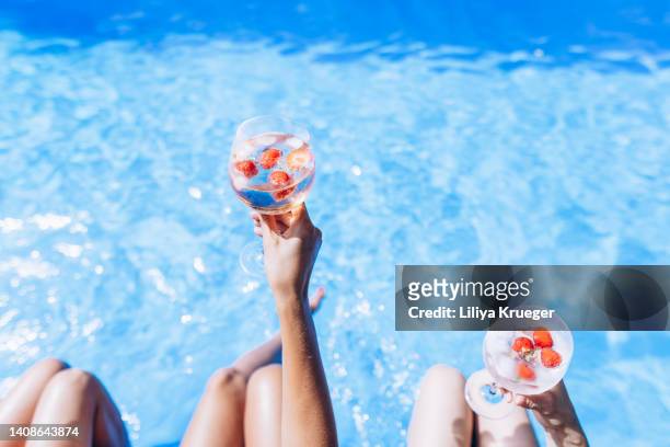womens on the side of the pool enjoying drinks on a hot sunny day. - holiday cocktail party stockfoto's en -beelden
