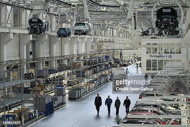 Employees walk below automated conveyors moving partially-assembled Volkswagen Touran and Tiguan cars at the Volkswagen factory on March 7, 2012 in...