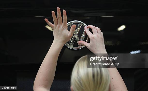 Female worker affixes the VW emblem onto a Volkswagen Touran car on an assembly line at the Volkswagen factory on March 7, 2012 in Wolfsburg,...