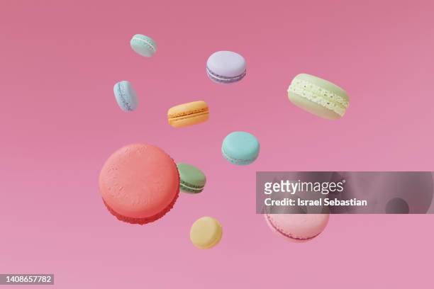 digitally generated image of several macarrons of different colors floating on a pink background. - flight food stock pictures, royalty-free photos & images