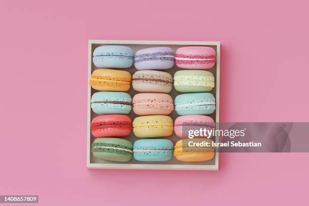 digitally generated image as view from above of a group of different colored macaroons inside a wooden box on a pink background. - macarons 個照片及圖片檔