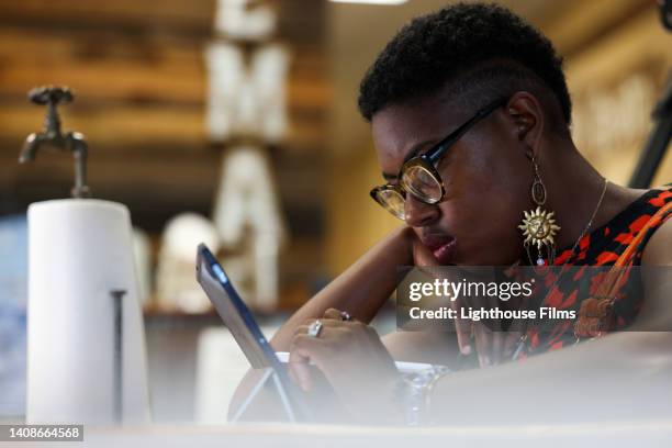 a concentrating african american women staring at a tablet - face look right stock pictures, royalty-free photos & images