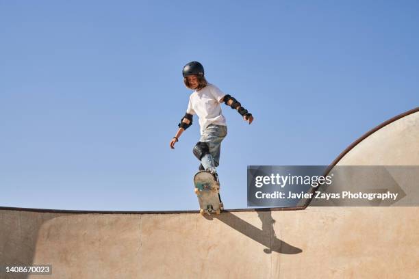androgynous young girl ready to skate in the skate park - skateboard halfpipe stock-fotos und bilder
