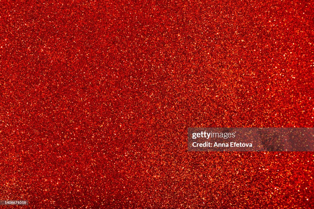 Red background made of sequins and lights. Holiday concept. Copy space for your design. Selective focus