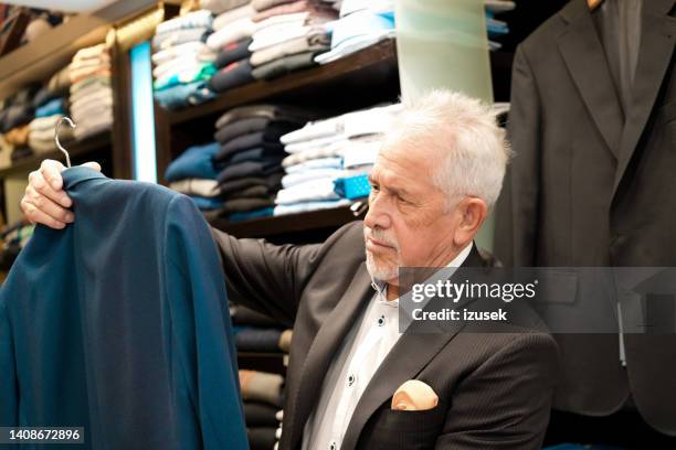 senior male customer examining navy blue suit - marineblauw jak stockfoto's en -beelden