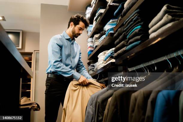 young male owner arranging suits in rack at showroom - suit rack stock pictures, royalty-free photos & images