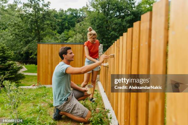 junges paar, das einen lattenzaun malt - zaun stock-fotos und bilder