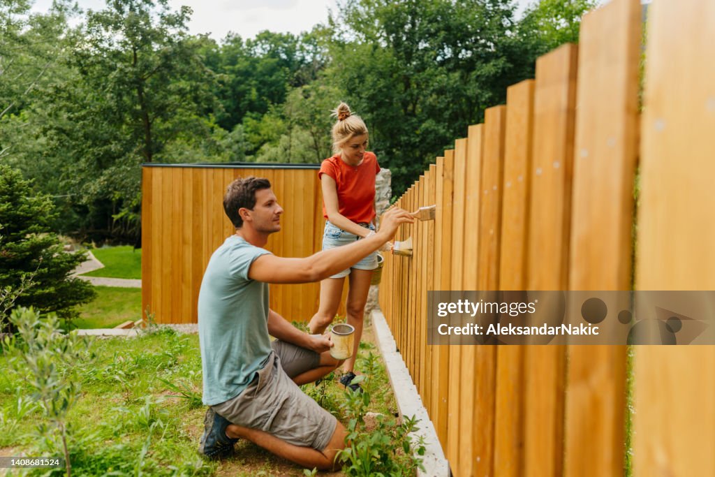 Young couple painting a picket fence