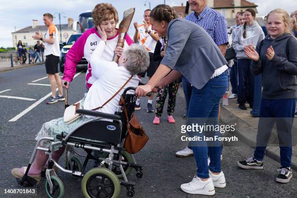 Batonbearer Jean Dixon MBE is greeted by her mother, Jean Buck and Jean's daughter, Hayley Hood after she carries the Queen's Baton during the...