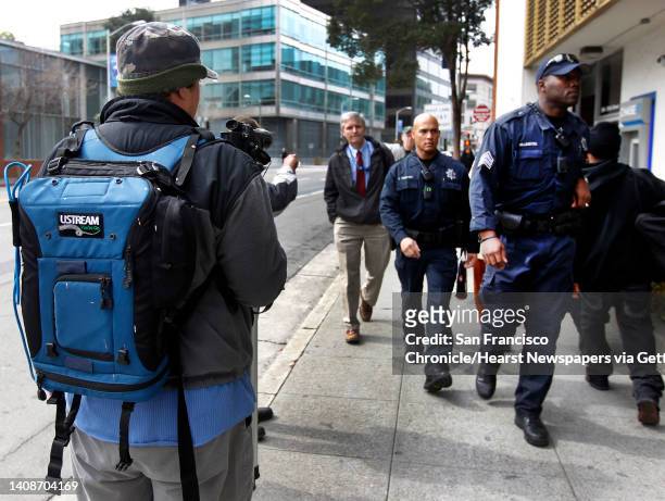 Video blogger Spencer Mills monitors activity by police officers while streaming live an Occupy Oakland action against banks in Oakland, Calif. On...